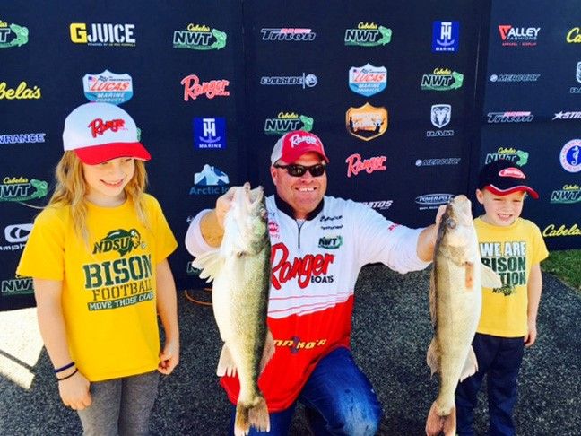 Larson posing with his two biggest catches and two kids