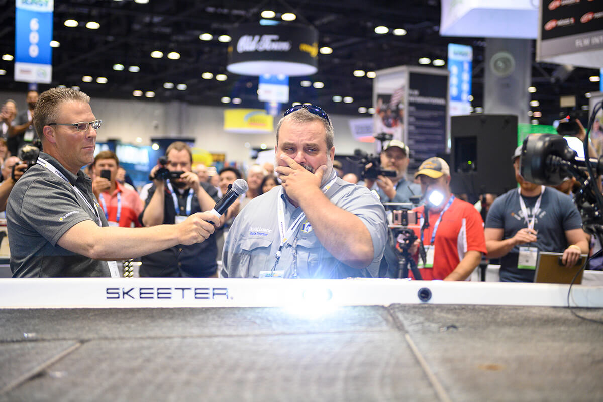 Veteran and angler David Lowrie looks at his boat in shock, surrounded by media at the ICAST sho