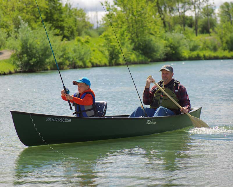 Man with child paddling and fishing in the Old Town Saranac Canoe